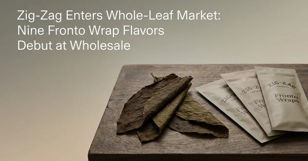 A whole fronto tobacco leaf displayed next to new Zig-Zag Fronto packaging on a wooden surface.